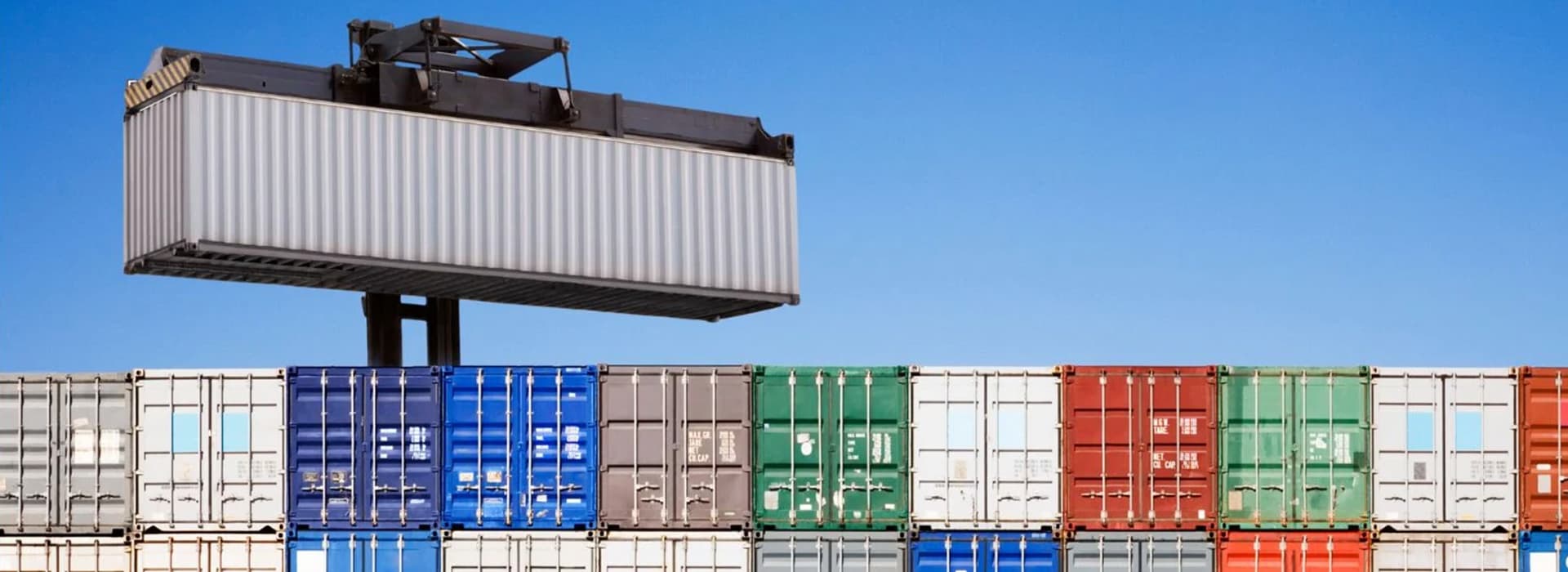 A shipping container lifted above a stacked row
